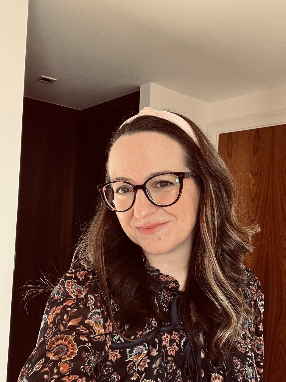 Jackie Lindsey smiling, wearing glasses and a floral blouse